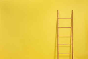 Modern wooden ladder on yellow background. Space for text