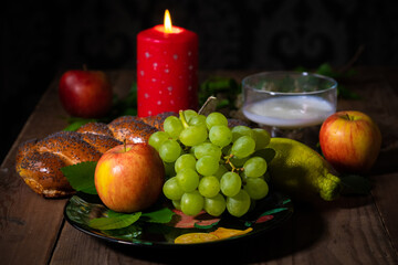 candles, apples and green grapes on a wooden table.