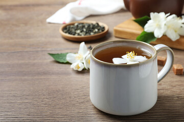Fototapeta na wymiar Cup of tea with fresh jasmine flower on wooden table. Space for text