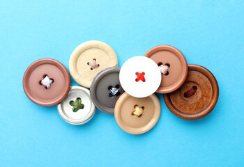 Many colorful sewing buttons on light blue background, flat lay