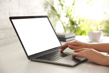 Woman working with modern laptop at white wooden table, closeup