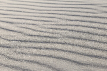 Fototapeta na wymiar Close-up of wavy patterns on a sandy surface on the beach with blur background.