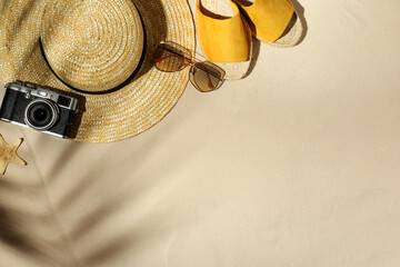 Flat lay composition with vintage camera and beach objects on sand. Space for text