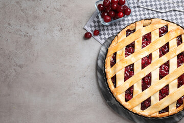 Delicious fresh pie and cherries on grey table, flat lay. Space for text