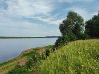 green slope near the river bank against the blue sky