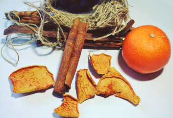 Cinnamon sticks, orange, dried apples and a small jute sack isolated against white-grey background. Closeup. Spices. Healthy life style. 