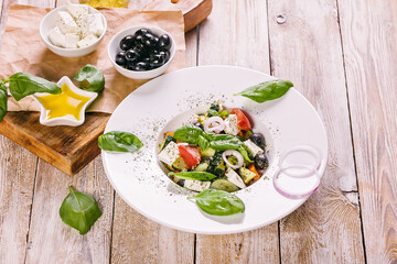 Greek salad in a white plate. Mediterranean vegetable salad with fresh basil, olives, olive oil and spices. Close-up