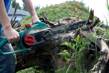 electric saw in action cutting wood. Man cutting wood with saw, dust and movements. Close-up of woodcutter sawing chain saw in motion, sawdust fly to sides.