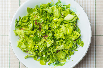 Fresh green salad of tomato and cucumber in plate on kitchen table.