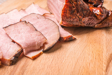 Sliced smoked boar on wooden board.