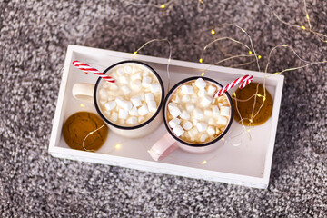 Two cups with cappuccino, a festive box with a gift, Christmas decorations