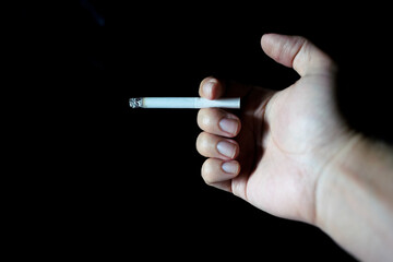 male hand holding cigarette dark background