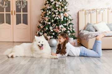 Christmas Child girl with dog Samoyed. New Year at home