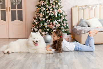 Christmas Child girl with dog Samoyed. New Year at home