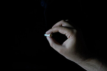 male hand holding cigarette dark background