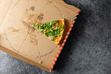 above view of last slice of pizza in cardboard box on stone kitchen counter