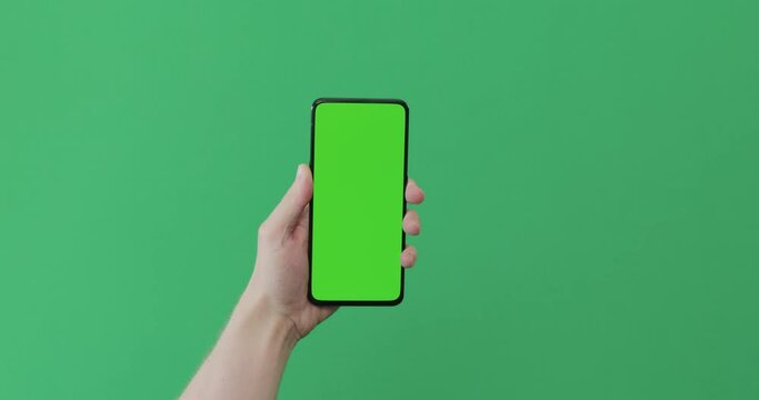 Young man hand touch smartphone with green screen on green background
