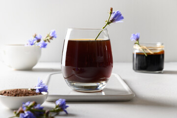 Chicory Root Coffee in glass and fresh flowers. Health Benefits. Instant and concentrate. Close up.