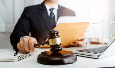 Justice and law concept.Male judge in a courtroom with the gavel, working with, computer and docking keyboard, eyeglasses, on table in morning light