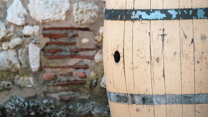 Close up of Old wooden barrel against a stone brick wall