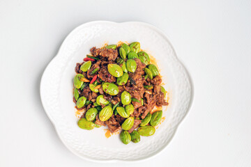 Stir fried bitter bean (Sator) with pork in white plate isolate on white background.Traditional Thai Food: Pad Ped Sator Moo.