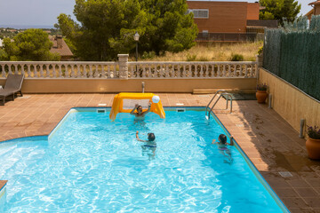 Three kids playing with a ball on a pool