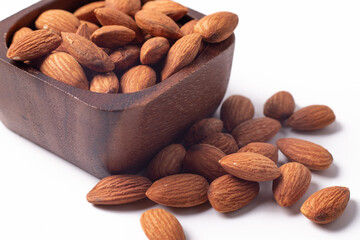 Almonds in a wooden cup on a white background