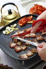 cooked samgyeopsal ( grilled pork belly BBQ ), being cut with scissors