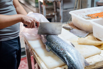 Worker steaking a fish with a cleaver knife