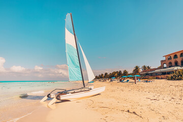 white catamaran blue sail on white sandy beach with retro effect. beach of Varadero in Cuba