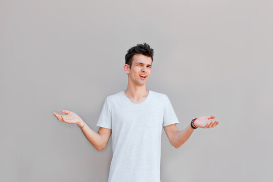 Closeup portrait of dumb clueless young man, arms out asking what's the problem who cares so what, I don't know. Isolated on white background. Negative human emotion, facial expressions, attitude