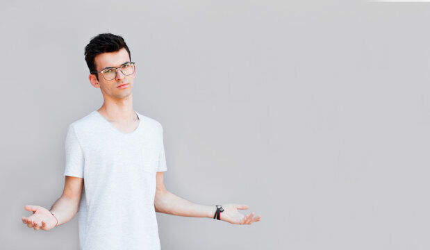 Closeup portrait of dumb clueless young man, arms out asking what's the problem who cares so what, I don't know. Isolated on white background. Negative human emotion, facial expressions, attitude