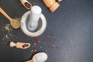 stone mortar and wooden spoons with spices on the table, copy space