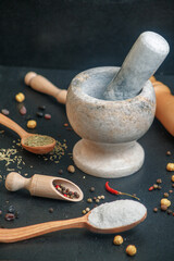 stone mortar with pepper and wooden spoon with spices on the table, side view