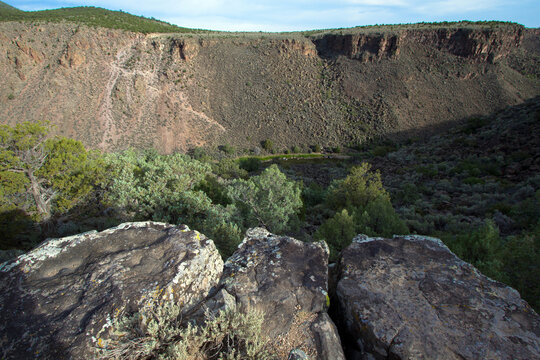 Dawn light on Rio Grande del Norte National Monument in New Mexico, with colorful moss rock in the foreground 