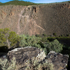 Dawn light on Rio Grande del Norte National Monument, with colorful moss rock in the foreground and extinct volcano Ute Mountain in distance