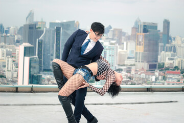 Businessman in suit and attractive sexy woman making dance of passion tango on the rooftop with...