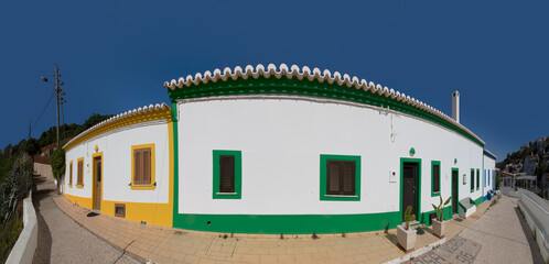 Fototapeta na wymiar portuguese house in the Algarve region with white walls and colorful framing and inscription verde (green) in the cobble stone