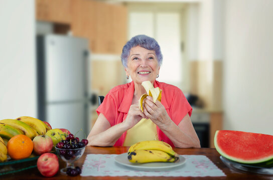 An elderly woman is enjoying a banana. She knows the potassium in bananas enters the bloodstream throughout the body. It is vital for cardiac and skeletal muscle function.