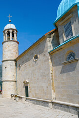 Fototapeta premium The blue dome and bell tower of the Temple of the Lady of the Rock on a background of blue sky. Island near Perast. Montenegro.