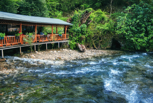 Forest cafe terrace on a mountain river with a grotto
