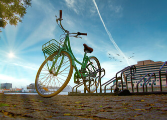 Fototapeta premium Vintage green bicycle parked on the edge of a port, sunny day