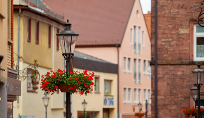 Fototapeta na wymiar Street lamp with flowers and a street in the background.