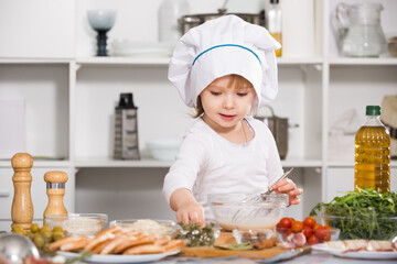 Young girl is satisfied of cooking sauce in the kitchen at home.