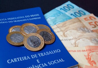Carteira de trabalho brasileira com cédulas e moedas. Dinheiro brasileiro. Conceito de salário e emprego. 