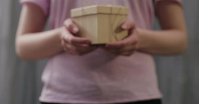 Slow motion young woman stand and show brown gift box with twine bow