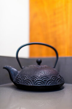 Tea traditional teapot on countertop table of zen minimalism home wooden wall background vertical closeup view of cast iron teaware