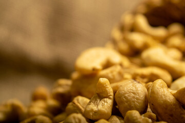 A pile of cashew nuts on burlap with a rough texture surface texture. Close up.