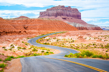 Curvy winding road and red sandstone rock formations desert landscape in Goblin Valley State Park in Utah summer