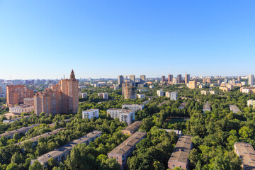 Fototapeta na wymiar High angle view of Moscow city shortly before sunset. Residential buildings stands between green trees. Clear blue sky.
